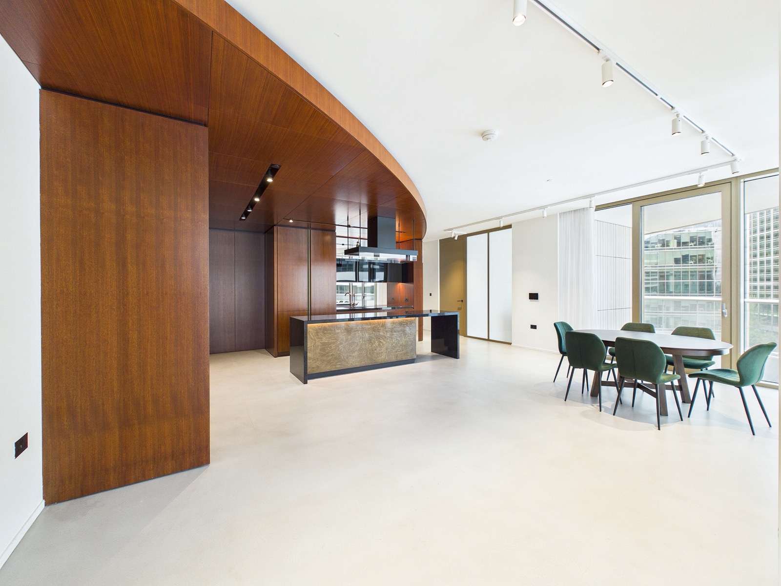 Open-plan kitchen and lounge under the curved walnut canopy — One Park Drive, Wood Wharf